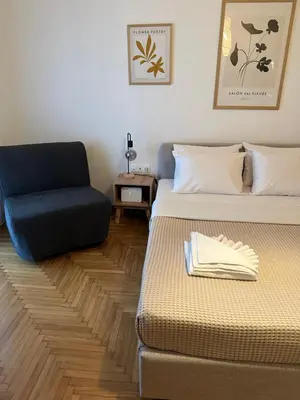 a room with two beds and a blue chair at Cozy Faliro home in Piraeus