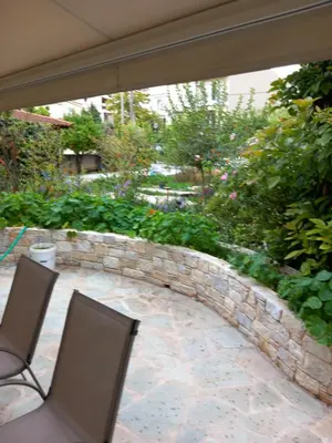 a patio with two chairs and a stone wall at pavlosloft in Leondárion