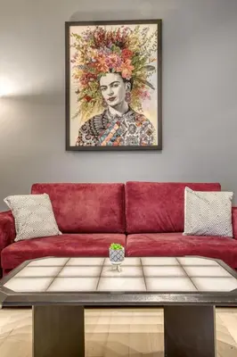 a red couch in a living room with a painting on the wall at Sweet and modern flat at Palaio faliro in Athens