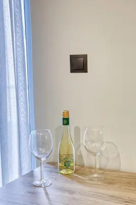 a bottle of wine and two wine glasses on a table at Sweet and modern flat at Palaio faliro in Athens