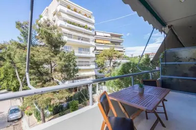 a balcony with a wooden table and chairs and a building at Sweet and modern flat at Palaio faliro in Athens