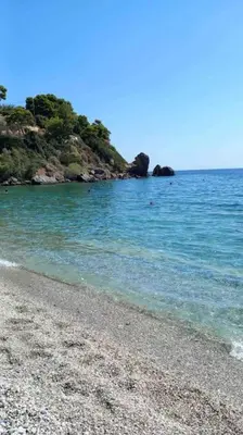 a beach with a rocky shore and blue water at The Beach House in Porto Rafti