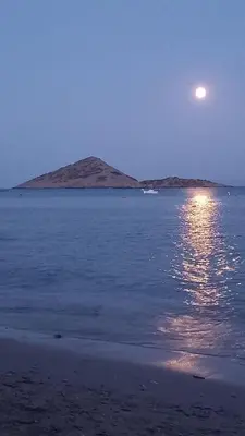 a full moon rising over the water with a beach at The Beach House in Porto Rafti