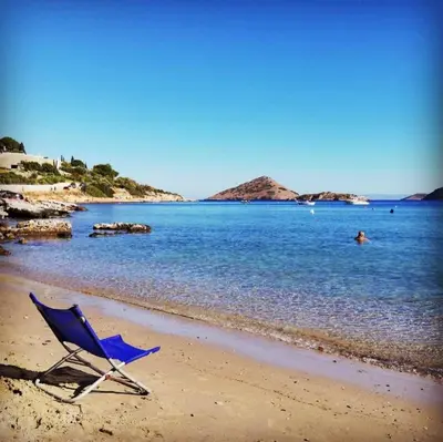 a blue chair sitting on a beach near the water at The Beach House in Porto Rafti