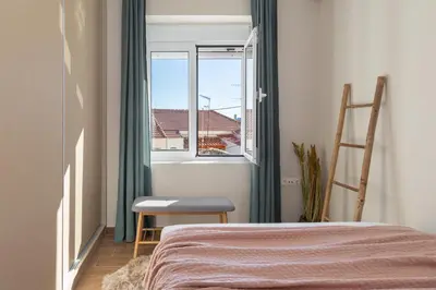 a bedroom with a bed and a chair and a window at Mikrolimano Gem: Serene 1BR Apartment in Piraeus