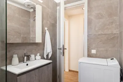 a bathroom with a sink and a washing machine at Mikrolimano Gem: Serene 1BR Apartment in Piraeus