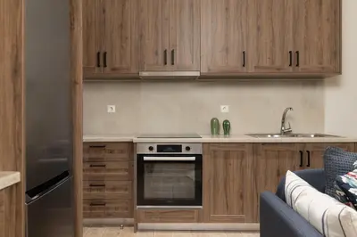 a kitchen with wooden cabinets and a stove at Mikrolimano Gem: Serene 1BR Apartment in Piraeus