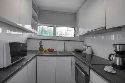 a white kitchen with a sink and a microwave at Luxury penthouse with stunning riviera view by GHH in Athens