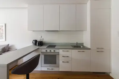 a kitchen with white cabinets and a sink and a chair at Athens Trikoupi Suite D1 in Athens