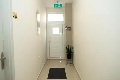 a hallway with a white door and a plant at Anesis Airport rooms 102 in Koropíon