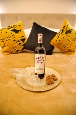 a bottle of wine and glasses on a bed at Suites Rania in Áyios Yeóryios