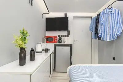 a small white room with a bed and a tv at The Oh Boy Studio in Athens in Athens