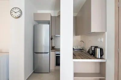 a kitchen with a refrigerator and a clock on the wall at Theia 1-Bedroom Apartment in Athens in Athens
