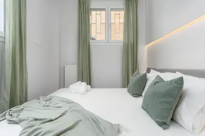 a white bed with green curtains and a window at Penelope Charming 2Bedroom Apartment in Athens in Athens
