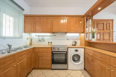 a kitchen with wooden cabinets and a washer and dryer at Calipso in Piraeus