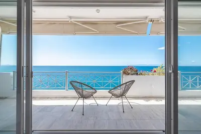 two chairs sitting on a porch looking out at the ocean at Calipso in Piraeus