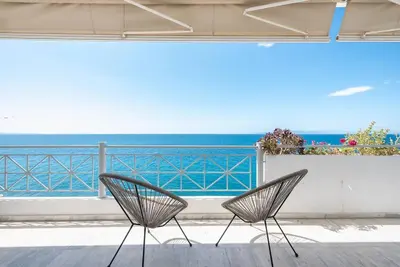 two chairs sitting on a balcony looking at the ocean at Calipso in Piraeus