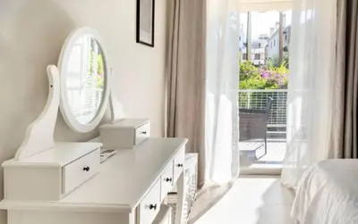 a white bedroom with a dressing table and a mirror at Seaside Beauty 5 min Vouliagmeni Beach in Athens