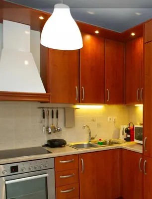 a kitchen with wooden cabinets and a sink and a light at Aqua Apartment Kallithea Athens in Athens
