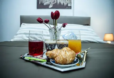 a tray of food with drinks and flowers on a bed at Aqua Apartment Kallithea Athens in Athens