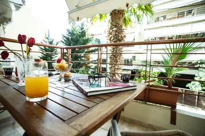 a wooden table with a glass of orange juice on a balcony at Aqua Apartment Kallithea Athens in Athens