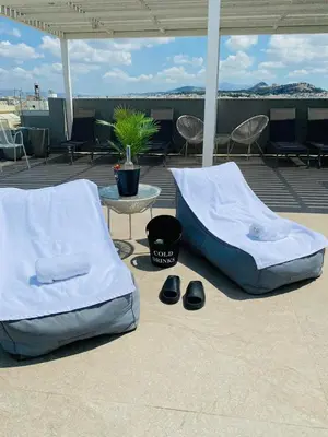 two beds and a table and chairs on a patio at NEW 2BD APRT with SHARED ROOFTOP POOL E2 in Athens