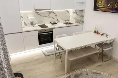 a white kitchen with a white table and chairs at The Golden home 1 in Piraeus