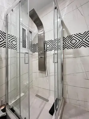 a shower in a bathroom with black and white tiles at Green House near Athens Center in Athens