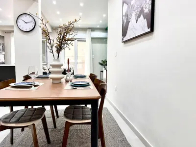 a dining room table with chairs and a clock on the wall at Green House near Athens Center in Athens