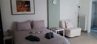 a bedroom with a bed and a white chair at Athenian Asty Guesthouse in Athens