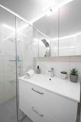a white bathroom with a sink and a mirror at Alkuoni lux flat at PFaliro in Athens