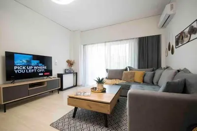 a living room with a couch and a tv at Alkuoni lux flat at PFaliro in Athens