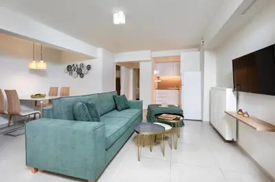 a living room with a green couch and a kitchen at Mystique One Bedroom Apartment by BluPine in Athens