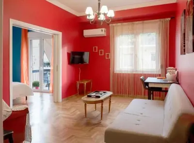 a red living room with a couch and a table at Casa de Colores, next to the metro in Athens