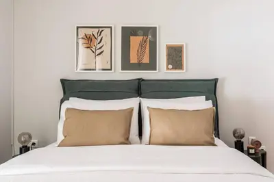 a bedroom with a white bed with four pictures on the wall at Radiant Retreat in Paleo Faliro by UPSTREET in Athens