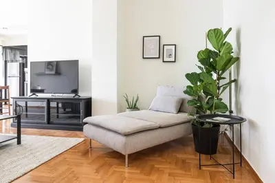 a living room with a couch and a potted plant at Radiant Retreat in Paleo Faliro by UPSTREET in Athens