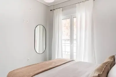 a white bedroom with a bed and a mirror at Radiant Retreat in Paleo Faliro by UPSTREET in Athens