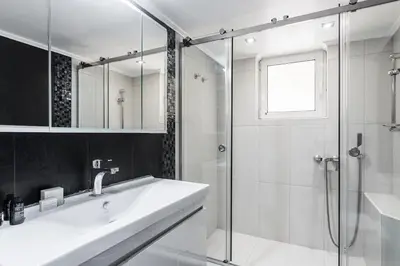 a white bathroom with a sink and a shower at Radiant Retreat in Paleo Faliro by UPSTREET in Athens