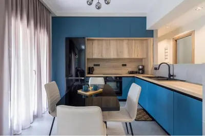 a kitchen with blue cabinets and a table and chairs at Blue Pearl at Glufada sea side in Athens