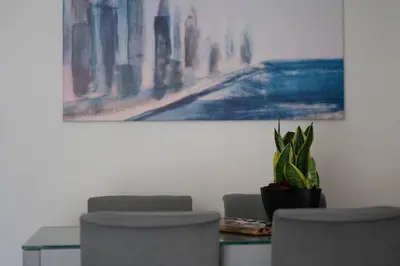 a dining room with a table and chairs and a painting at Beachfront apartment in Voula w/balcony in Athens