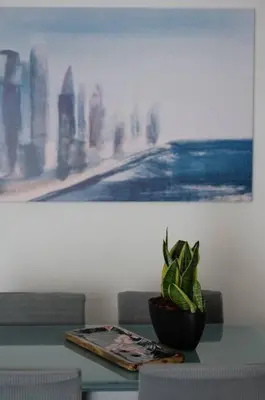 a potted plant sitting on a table in front of a painting at Beachfront apartment in Voula w/balcony in Athens