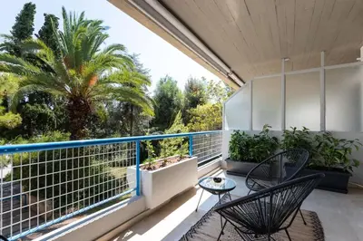 a balcony with two chairs and a palm tree at Beachfront apartment in Voula w/balcony in Athens