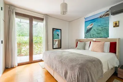 a bedroom with a bed and a large window at Private Garden Home next to the beach and market in Athens
