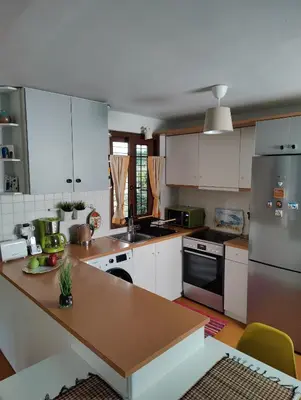a kitchen with white cabinets and a wooden counter top at Private Garden Home next to the beach and market in Athens