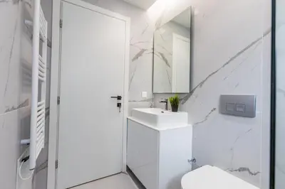 a white bathroom with a sink and a mirror at Varkiza Luxury Suites by Raise in Vari
