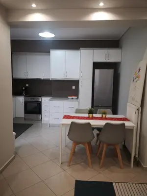 a kitchen with white cabinets and a table and chairs at Athenian Luxury apartment, near metro station Chalandri, Nu 1 in Athens