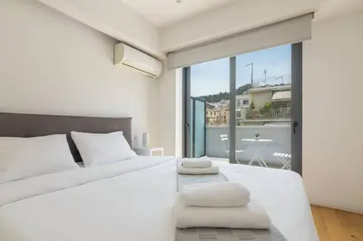 a bedroom with a white bed and a large window at Athens Trikoupi Suite E1 in Athens