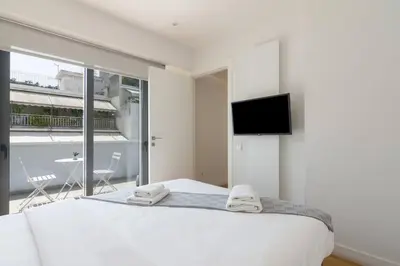 a bedroom with a white bed with a flat screen tv at Athens Trikoupi Suite E1 in Athens