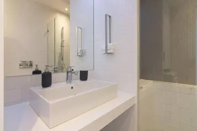 a white bathroom with a sink and a shower at Athens Trikoupi Suite E1 in Athens