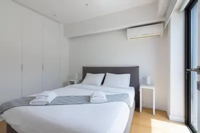 a white bedroom with a white bed and a window at Athens Trikoupi Suite E1 in Athens